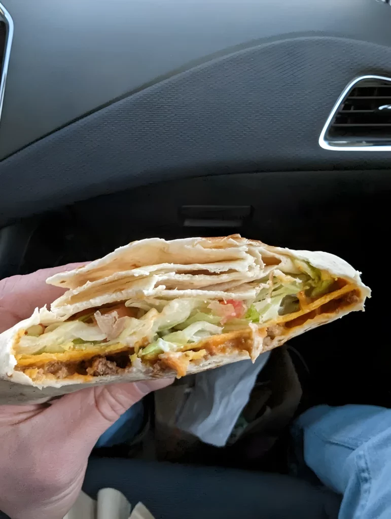 Holding a Taco Bell Crunchwrap Supreme in hand.